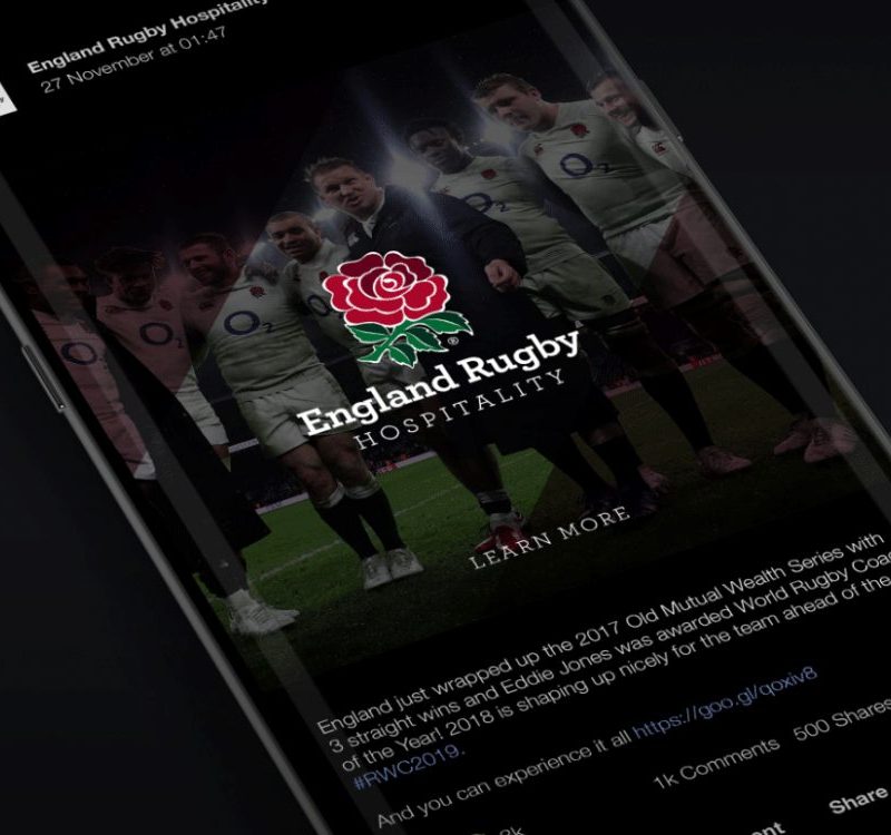 A mobile phone screen displaying a Facebook post featuring England Rugby Hospitality, with players standing together on a rugby field, the red rose England Rugby logo, and promotional text about hospitality packages.