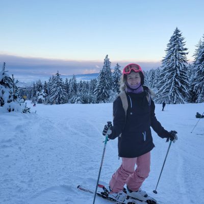 Team member Althea skiing on a snowy mountain with clear blue skies