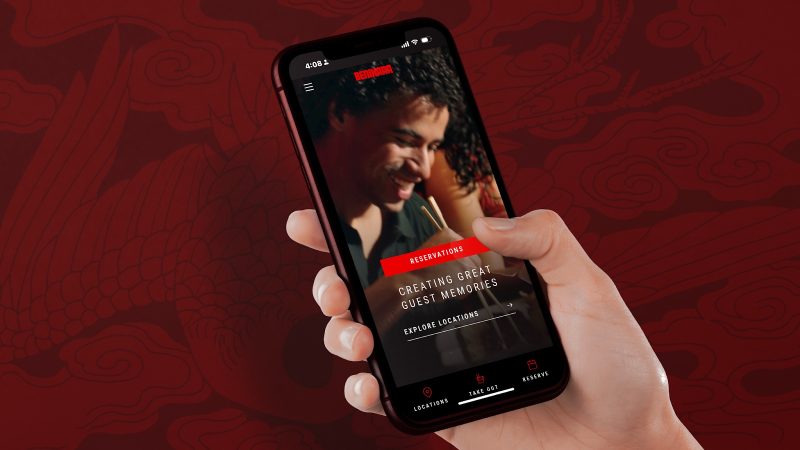 Hand holding iPhone showing the Benihana website homepage
