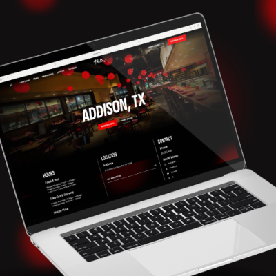 Open laptop displaying the RA Sushi restaurant website with the Addison, TX location page. The screen shows a restaurant interior photo, business hours, contact information, and a red 'Reservations' button. The laptop is positioned at an angle on a red and black blurred background.