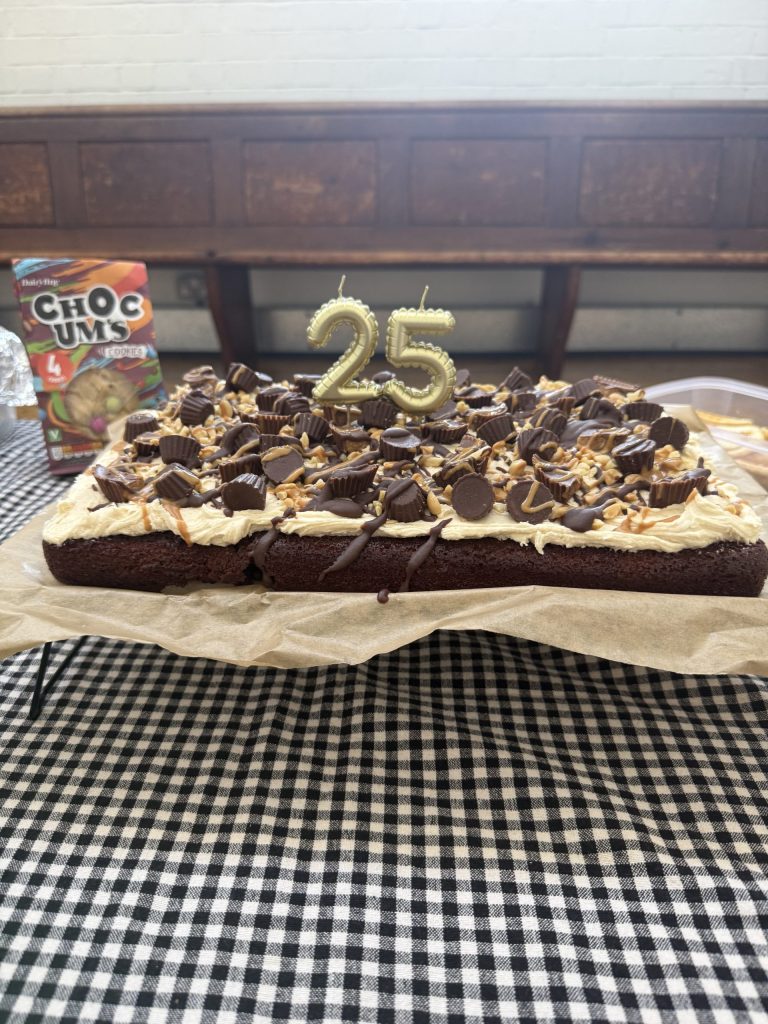 A large single layer cake, decorated with thick chocolate icing, chocolate pieces and candles.