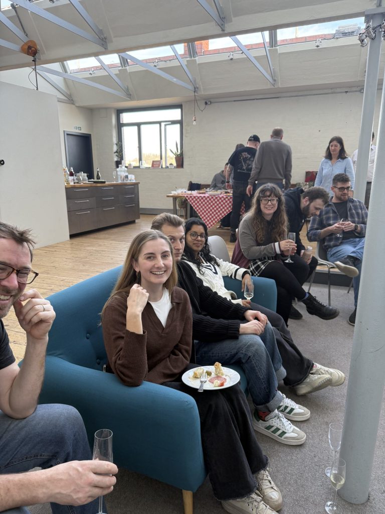 People sitting on a blue sofa in a large room smiling for a photo.