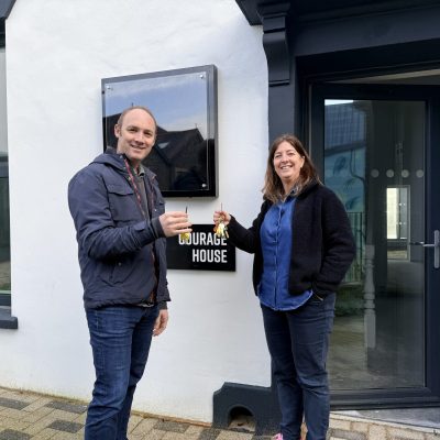 A man and a woman holding keys to the new office and smiling at the camera.