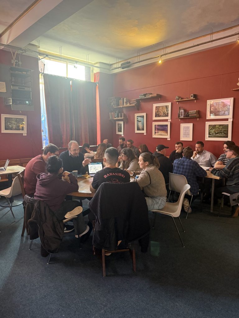 Fanatic employees split into teams around separate tables, discussing ideas.