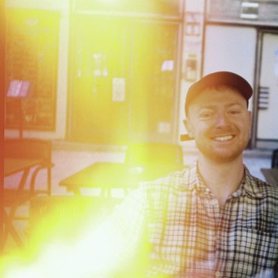 Brad smiling at a café in Budapest, captured on film with a warm lens flare