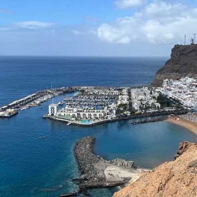 Aerial view of a marina and beach in Gran Canaria, with white buildings, moored boats and deep blue water