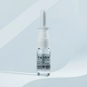 Clear Vaion NAD+ nasal spray bottle with white applicator and label showing product details, standing against a soft light blue background.