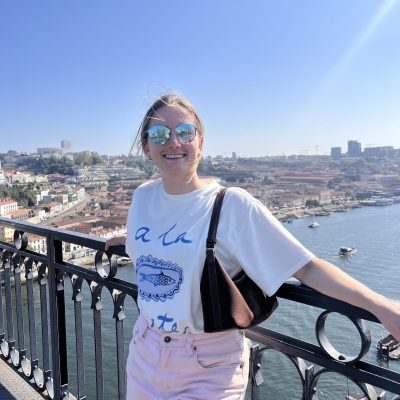 Althea smiling on a scenic viewpoint above Porto, Portugal, with the city and river behind her.