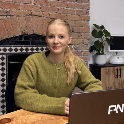 Emily in a green cardigan sitting behind a laptop