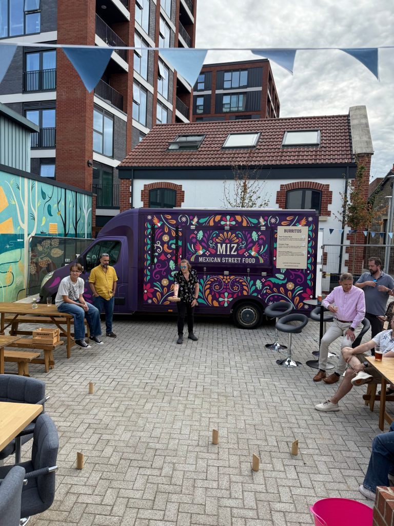 Guests socialise in a courtyard with bunting, picnic tables and a colourful Mexican street-food truck.