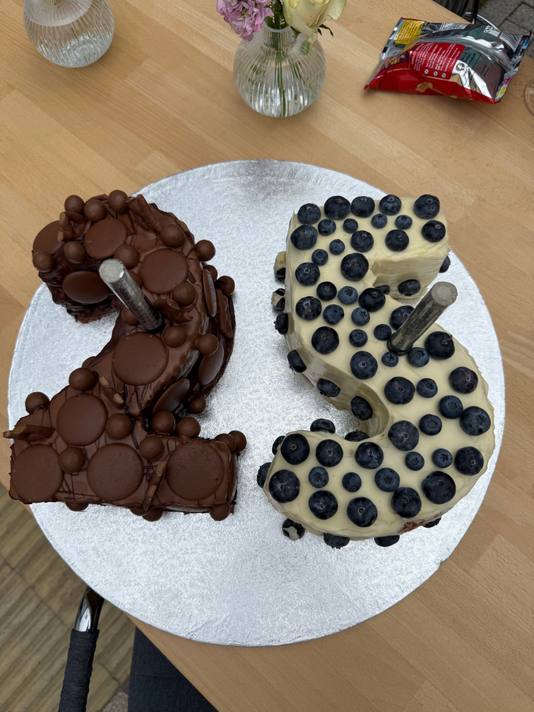 Two number-five celebration cakes form “25”: one covered in chocolate sweets and one decorated with blueberries.