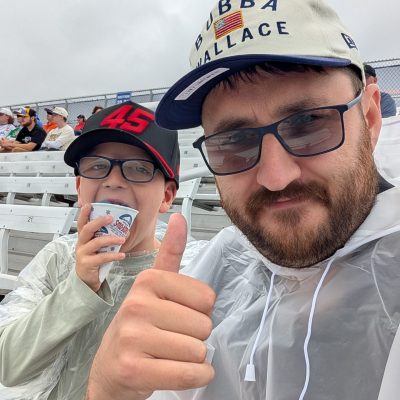 A selfie of Thomas and his son at a NASCAR race, wearing waterproof ponchos hats